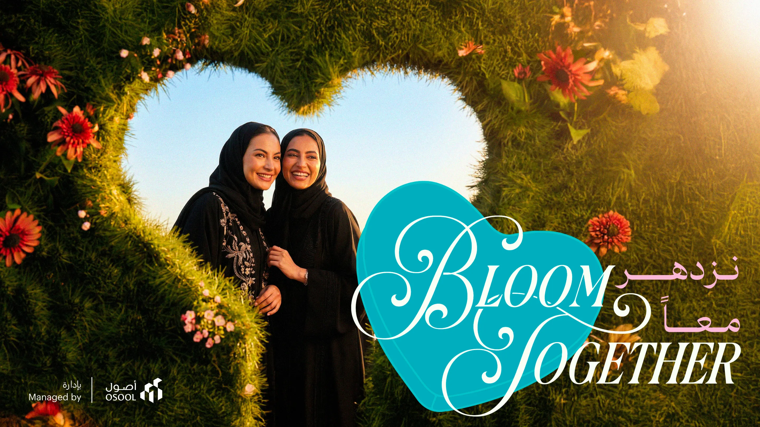 Bloom Together key visual: two women framed by a heart shaped hedge of flowers, with the title in English and Arabic